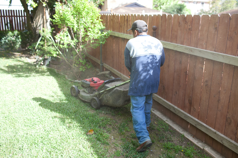 Worker Mowing Backyard Lawn at Private Residence